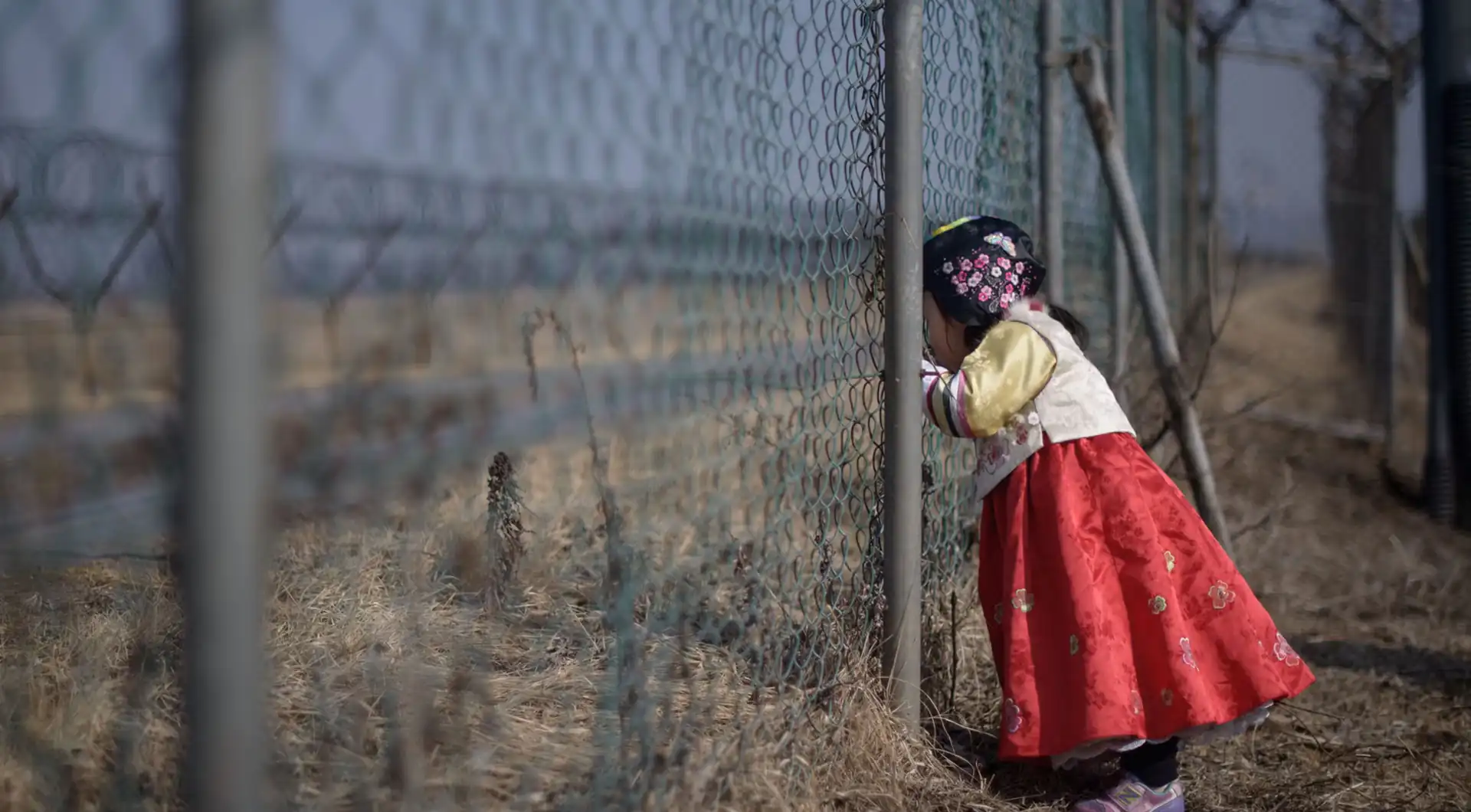 A north korean girl peeps through a border fence in the demilitarized zone